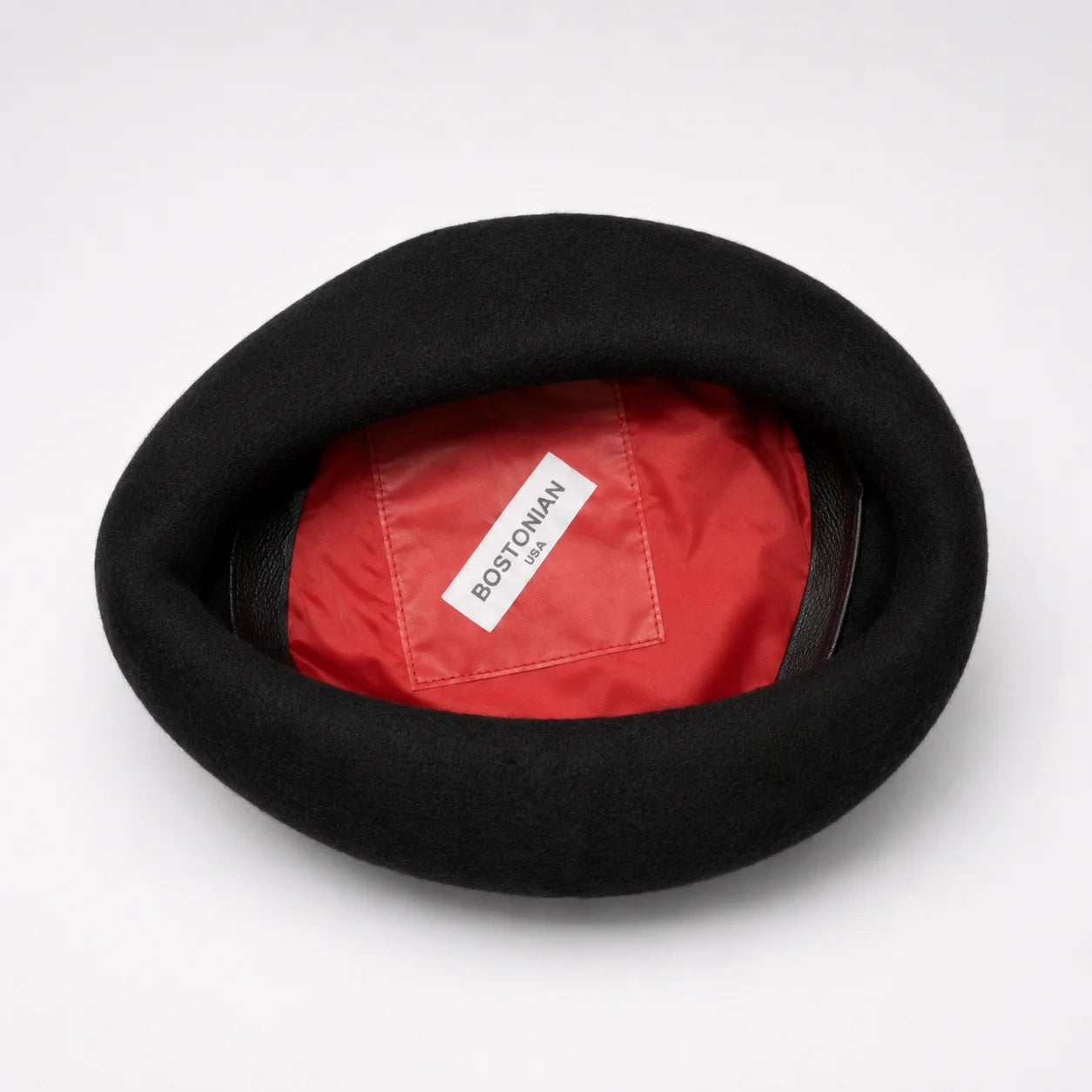 Black beret with a red interior and visible brand label on a white background