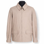 A light beige zip-up jacket with a pointed collar and two front flap pockets, displayed on a black mannequin torso against a white background.