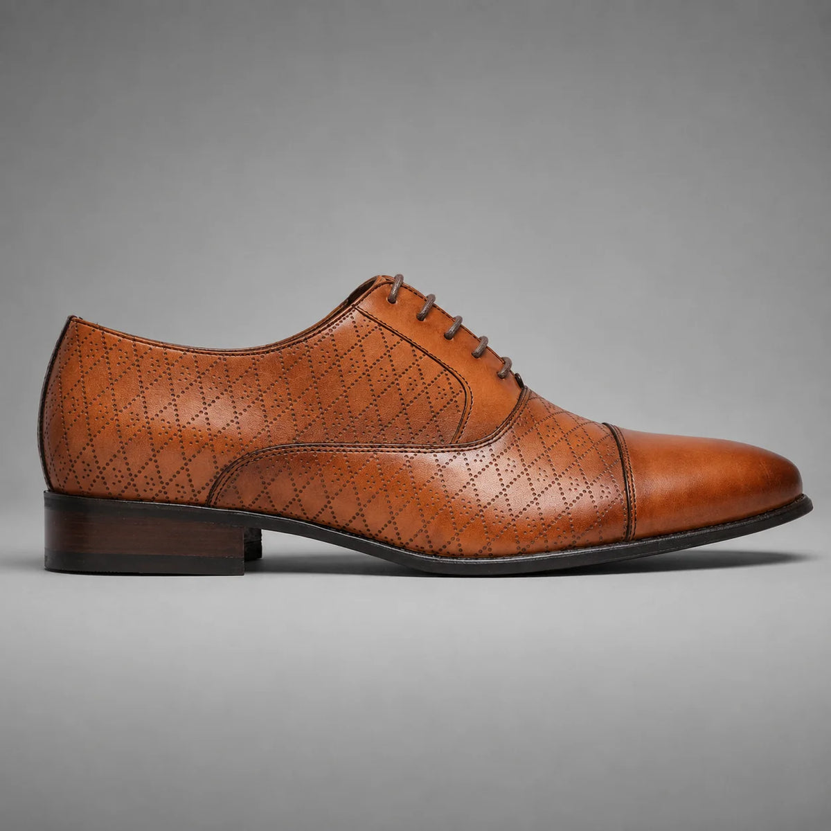 A single brown leather lace-up dress shoe with a cap toe and embossed geometric pattern, shown in profile against a neutral gray background.