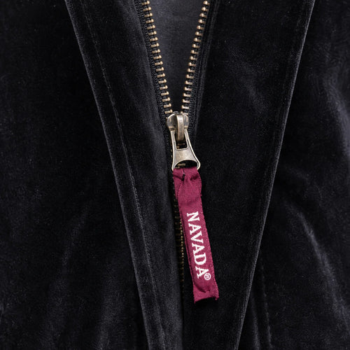 Close-up of a black velvet zippered garment with a silver zipper pull featuring a burgundy tab printed with the brand name 'NAVADA'.
