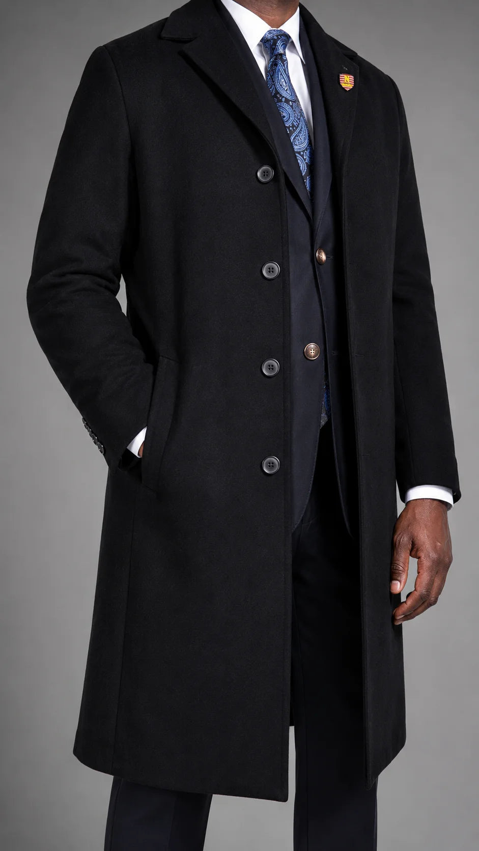 A man wearing a black Navada Clothing cashmere blend overcoat in a studio setting against a neutral grey studio backround